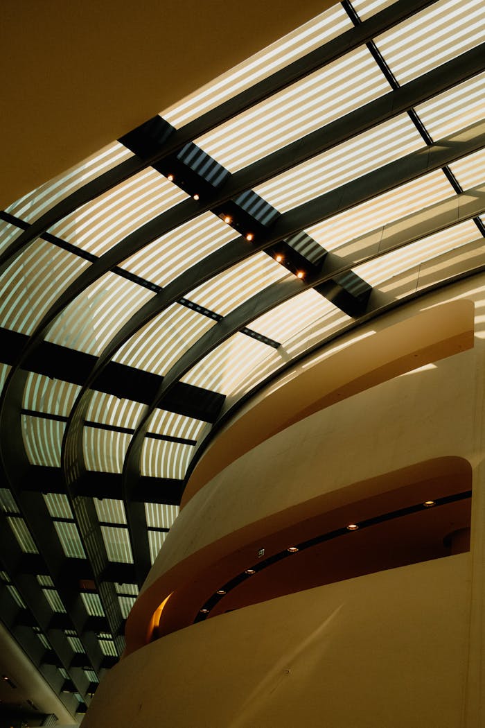Abstract view of a modern building's geometric ceiling structure with natural light filtering through.