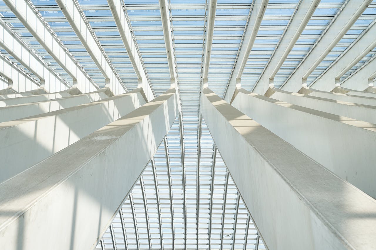 A striking upward view of a modern ceiling structure featuring geometric beams and glass panels.